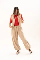 Pantalon tipo babucha de color beige, con silueta relajada y acabado suave tipo piel de durazno. Presenta cintura regulable con cordón y elástico en los tobillos que genera una forma abuchonada.