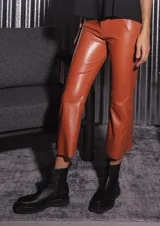 Pantalón de tela engomada color camel, de corte capri semi oxford y tiro medio-alto. Presenta bolsillos traseros y cierre con botón metálico.