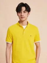 Chomba amarilla de corte slim, con cuello clásico, cartera de dos botones y logo de Tommy Hilfiger bordado en el pecho.