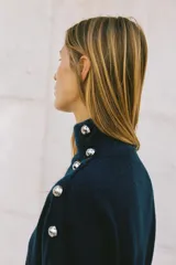 Jersey de punto de tacto suave, color azul petróleo, con cuello subido y manga larga. Presenta detalle de botones metálicos en el hombro y en los puños.