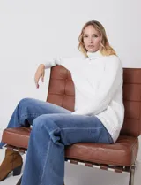 Polera de punto grueso color blanco, con cuello alto, mangas largas de corte ranglan y diseño de texturas combinadas.