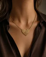 Collar de goldfilled dorado con cadena de eslabones y un dije en forma de corazón calado compuesto por la palabra "Mom" repetida.