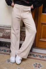 Pantalón tejido de punto color beige, de corte holgado y perneras anchas, con cintura elástica y cordón ajustable.