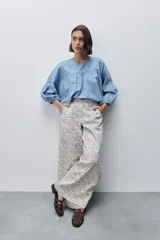 Pantalón de tiro alto con silueta amplia y piernas rectas, confeccionado en algodón con estampado floral. Cuenta con cierre frontal de botón y cremallera, y bolsillos laterales funcionales.