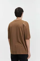 Remera de manga corta color gris oscuro, con corte holgado, hombros caídos y escote redondo. Presenta un logo estampado en el pecho con la inscripción "GALLERY DEPT." en color naranja.