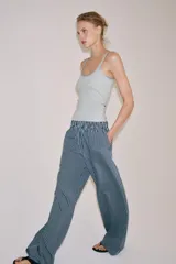 Pantalón de tiro medio con pierna ancha y cintura elástica, confeccionado en mezcla de viscosa con diseño de rayas verticales en tonos mostaza y marrón.