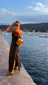 Vestido largo de lino color negro, con escote decorado con volados en tono terracota y tiras finas. Presenta tajos laterales en la falda y espalda descubierta.