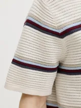 Sweater polo de tejido de punto en color beige, con diseño de rayas horizontales en tonos bordó, azul y celeste. Cuenta con cuello camisero y cartera de tres botones.