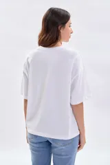 Remera blanca de manga corta con corte holgado y estampa central pequeña con diseño de flor y marco a cuadros.