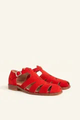 Sandalias de gamuza color marrón, estilo romano con diseño en T, tiras con aberturas laterales y cierre de hebilla metálica en el tobillo. Cuenta con tacón bajo de madera.