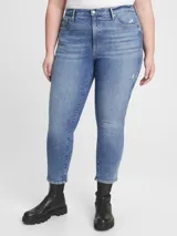 Jean de corte slim y tiro alto, con diseño de cinco bolsillos y cierre frontal con botón y cremallera. Presenta un lavado azul medio con efecto desgastado y pequeños detalles de roturas sutiles en los bolsillos y muslo.