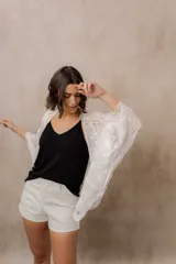 Kimono marfil de silueta amplia, confeccionado en tela con bordados florales y detalles calados. Cuenta con mangas amplias tres cuartos, frente abierto y terminaciones decorativas.