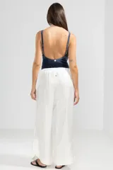 Pantalón de lino italiano color blanco con hilo metalizado, corte recto, talle medio, cintura elástica en la parte trasera y bolsillos delanteros.