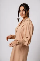 Vestido corto color tostado, con cuello solapa, abotonado al frente y mangas 3/4 con puños fruncidos.