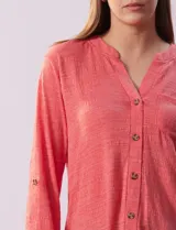 Blusa Ninety color beige con textura, cuello base con escote en V y abertura central con botones. Tiene un bolsillo en el pecho y mangas 3/4 regulables con presilla y botón.