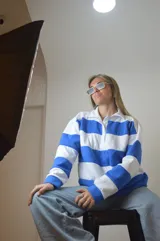 Sweater de punto a rayas horizontales azules y blancas, con cuello polo y cierre parcial con cremallera.