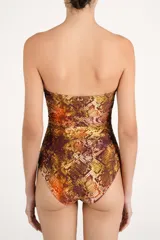 Malla enteriza strapless con estampado de serpiente en tonos marrones y dorados, con detalle de abertura en el escote bordeada con cuentas oscuras y fruncidos laterales.