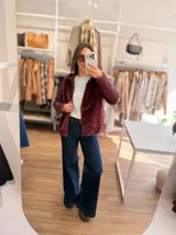 Campera con cuerpo de piel sintética tipo teddy y mangas acolchadas. Presenta cierre frontal, capucha y diseño de corte recto.