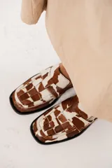Mocasines de cuero con estampado animal print de vaca, con diseño enrejillado en la capellada y suela de goma negra.