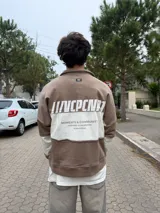Buzo tipo polo de corte relajado y fit boxy, con diseño de bloques de color en bordó y blanco. Presenta cuello camisero con cierre frontal parcial y logo bordado en el pecho.