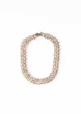 Pulsera dorada con triple hilera de strass y cierre desplegable.