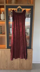 Vestido largo bordó sin mangas, de corte recto y acabado satinado, con detalles de aberturas laterales en el bajo.
