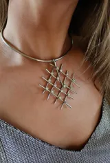 Gargantilla rígida plateada con dije geométrico de alpaca con forma de grilla y apliques de strass.