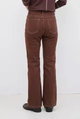 Pantalón tipo jean de corte recto y tiro medio, color burdeos, con costuras a tono y abertura lateral en el ruedo.