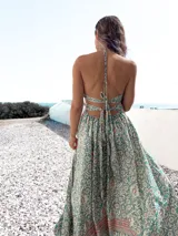 Vestido largo de tirantes con estampado floral en tonos celeste, blanco y rosa. Tiene escote halter y espalda descubierta con lazos.