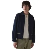 Campera Rhythm Arugam Twill azul marino, con cierre frontal, cuello camisero y bolsillos delanteros. Presenta detalles bordados en amarillo y blanco en los bordes de los bolsillos.