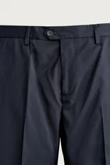 Pantalón de traje regular fit negro, confeccionado en lana italiana, con bolsillos laterales, bolsillos traseros de vivo con botón y cierre frontal de cremallera y botón.