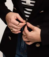 Blazer femenino de sastrería confeccionado en punto roma, con cuello solapa, cierre frontal con botones decorativos y diseño estructurado.