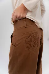 Pantalón de gabardina de algodón color negro, con calce barrel, cintura media baja, recortes de diseño y detalle de botones en el ruedo para ajustar el volumen.
