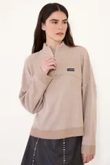 Sweater negro de punto con cuello alto y cierre frontal parcial de cremallera, de manga larga y diseño holgado con hombros caída.