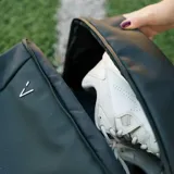 Mochila deportiva negra de diseño minimalista, con múltiples compartimentos, incluyendo espacio térmico para raquetas, bolsillo inferior ventilado para calzado y compartimento interno para laptop.