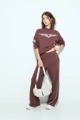 Pantalón babucha negro de silueta amplia y caída relajada, con detalle de líneas blancas laterales y cintura elastizada.