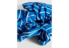 Scrunchie para el pelo de color azul con estampado de rayas blancas finas.