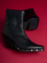 Botas negras de caña baja con punta fina y detalle de tachas plateadas en la suela.