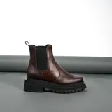 Bota tipo Chelsea de cuero vacuno, con suela de goma track de doble altura y elásticos laterales. Presenta una horma de punta cuadrada.