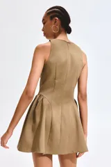 Vestido corto marrón sin mangas, con escote redondo y cierre oculto en la espalda. Cuenta con un diseño entallado en el cuerpo y una pollera acampanada con frunces en los laterales de la cadera.