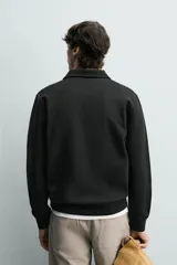 Sudadera polo de corte regular, confeccionada en tejido técnico interlock de algodón con elasticidad. Presenta cuello solapa, cierre frontal de cremallera y manga larga con puños acabados en rib.