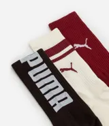 Kit de tres pares de medias deportivas Puma de caña larga. Un par es beige con dos rayas marrones y logo de Puma. Otro par es blanco liso. El tercer par es marrón oscuro con dos rayas blancas y logo de Puma. Todas están confeccionadas en algodón.