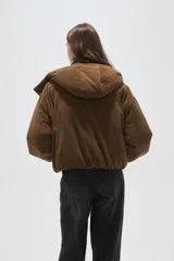 Campera puffer de color beige con cuello alto, capucha desmontable, cierre frontal y bolsillos laterales. Diseño de corte holgado con puños elásticos.