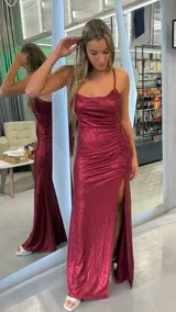 Vestido largo de fiesta color bordó con acabado brillante. Presenta escote redondo con drapeado en el busto, tirantes finos cruzados en la espalda con cierre de cordones y detalle de fruncido lateral con tajo profundo en la pierna.