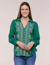Camisa de estilo boho, color verde, con cuello camisero, escote en V y botonadura frontal con botones perlados. Cuenta con una pechera con bordados geométricos y florales a contraste, mangas largas abullonadas con puños abotonados y delicados bordados dispersos.