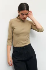 Polera de algodón color blanco, con cuello alto y mangas tres cuartos. Presenta un diseño ajustado al cuerpo con costuras decorativas en las sisas.