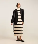 Vestido midi de punto con cuello alto y mangas largas. Diseño recto con rayas horizontales negras sobre fondo crudo y aberturas laterales.
