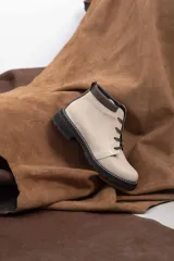 Borcego de cuero vacuno color marrón caramelo con acabado mate, estilo combate y caña baja. Cuenta con cordones marrones, panel de gamuza oscura en el cuello y suela de caucho negra tipo tractor con costura blanca visible.