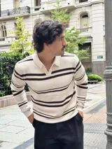 Buzo tejido de punto con diseño a rayas horizontales en color beige y marrón. Presenta cuello tipo polo con cierre frontal parcial y puños acanalados.