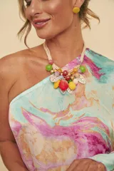 Collar corto con múltiples tiras de cordón beige en el cuello y un vistoso dije central con forma de racimo de frutas, compuesto por cuentas de resina de colores, fresa, piña y hojas blancas con bordes dorados.
